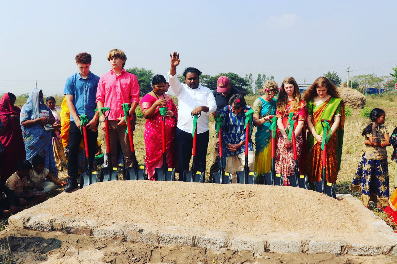Man praising God in India with others over new ground breaking for hospital