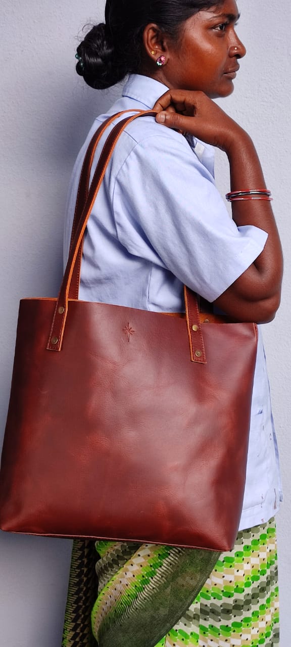 Indian woman artisan with brown leather bag on shoulder, top of bag sits just above waist